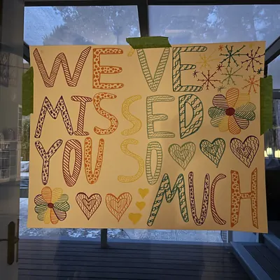 A hand-lettered “We’ve missed you so much” sign taped to a glass door.